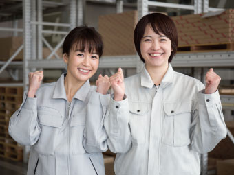 ガッツポーズをする作業服の女性2人